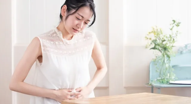 便秘でお腹を押させている女性